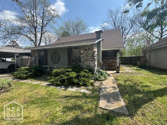 view of front of property with stone siding, a front lawn, and fence