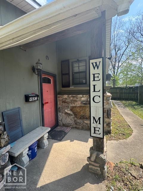 doorway to property with fence and stone siding