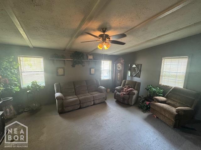 living area featuring carpet floors, a textured ceiling, and a ceiling fan