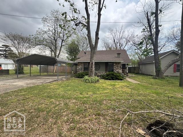 view of front facade with a detached carport, stone siding, a front yard, and concrete driveway