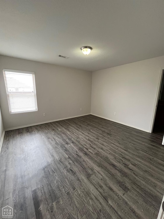 3828 Remington Dr, Jonesboro, AR 72404 - empty room with dark wood finished floors, visible vents, and baseboards