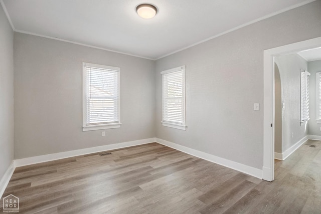 spare room with ornamental molding, wood finished floors, and baseboards
