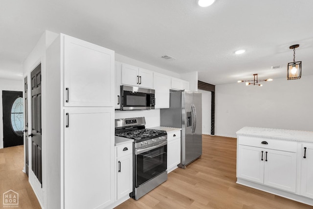 kitchen with white cabinets, appliances with stainless steel finishes, light wood-type flooring, visible vents, and pendant lighting