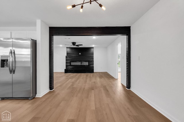 hall featuring baseboards, a notable chandelier, and light wood-style floors