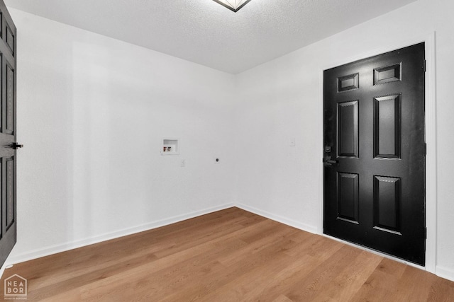 empty room with a textured ceiling, baseboards, and wood finished floors