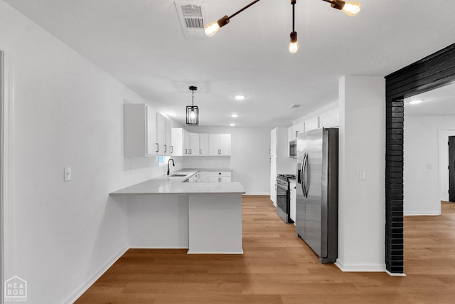 kitchen with baseboards, white cabinets, stainless steel appliances, and a peninsula