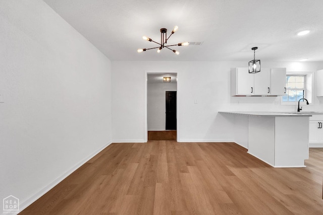 kitchen with light wood-type flooring, white cabinets, baseboards, and a notable chandelier