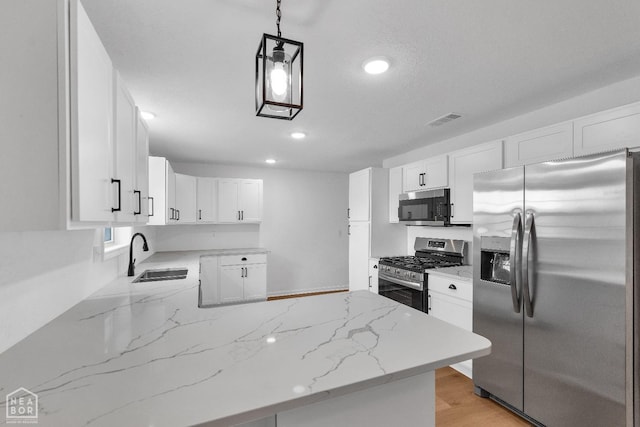 kitchen featuring visible vents, light stone countertops, a sink, a peninsula, and stainless steel appliances