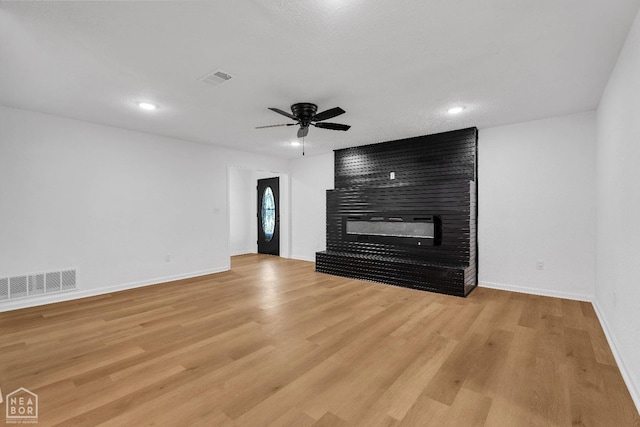 unfurnished living room featuring a ceiling fan, baseboards, visible vents, and a fireplace