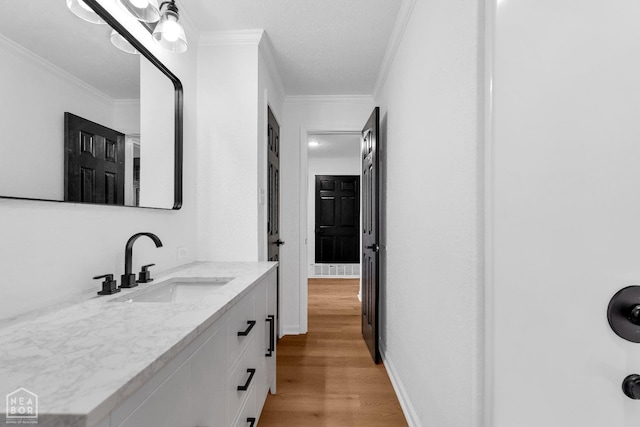 bathroom featuring ornamental molding, wood finished floors, and vanity