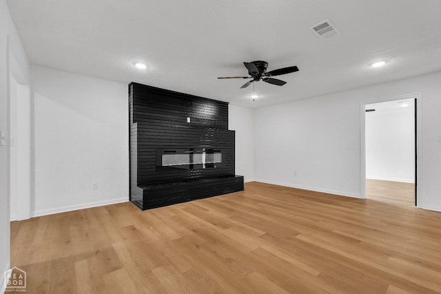 unfurnished living room featuring baseboards, light wood finished floors, ceiling fan, and a fireplace