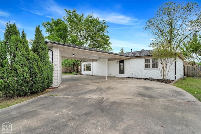 view of front of property with concrete driveway, fence, and a carport
