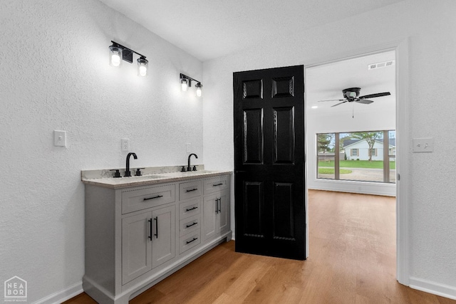 bathroom featuring a textured wall, visible vents, a sink, and wood finished floors