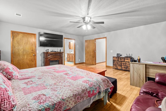 330 Greene 730th Rd, Paragould, AR 72450 - bedroom with hardwood / wood-style flooring, ceiling fan, ensuite bath, and a fireplace