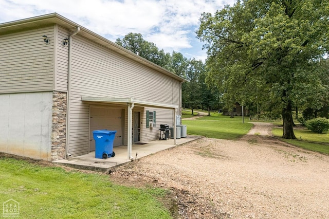 330 Greene 730th Rd, Paragould, AR 72450 - view of property exterior with a lawn, a garage, driveway, a patio area, and stone siding