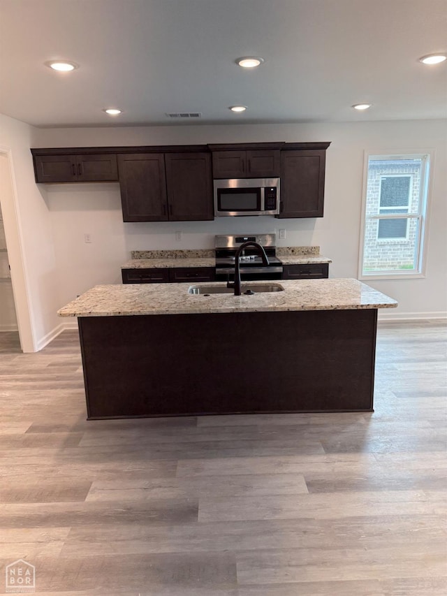5633 Morgan Dr, Jonesboro, AR 72401 - kitchen featuring appliances with stainless steel finishes, dark brown cabinetry, a sink, light stone counters, and recessed lighting