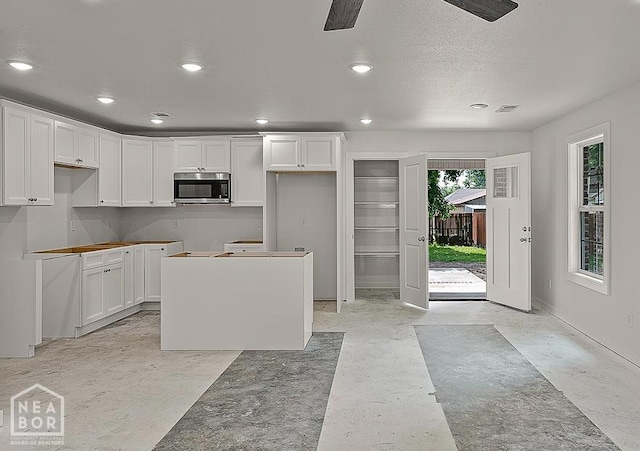 220 Stewart, Monette, AR 72447 - kitchen featuring stainless steel microwave, a kitchen island, white cabinetry, recessed lighting, and baseboards