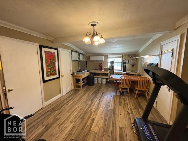 1207 Basil St, Corning, AR 72422 - dining room featuring wood finished floors, a wall mounted air conditioner, crown molding, and a chandelier