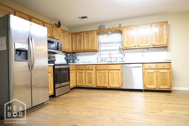 5703 Cedar St, Paragould, AR 72450 - kitchen featuring appliances with stainless steel finishes, light wood finished floors, light countertops, and a sink