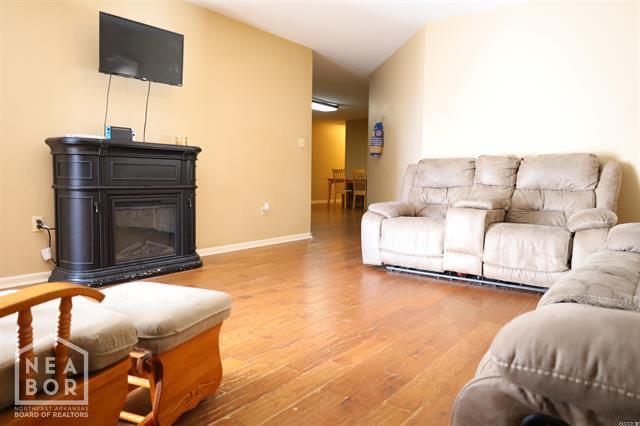 5703 Cedar St, Paragould, AR 72450 - living room with wood finished floors, a glass covered fireplace, and baseboards