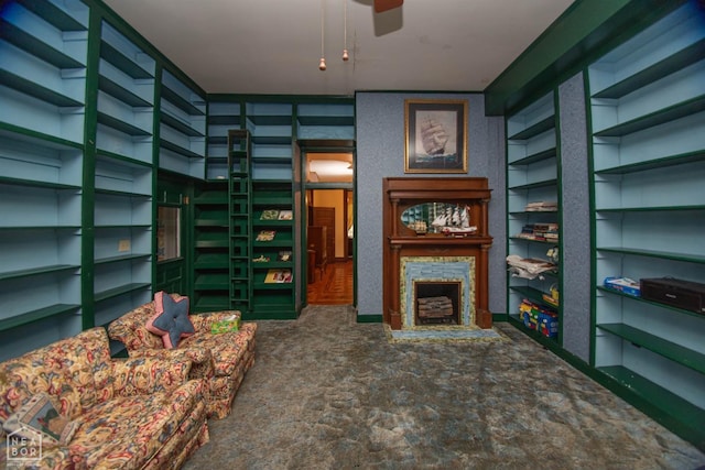 living area featuring a fireplace, built in features, and a ceiling fan