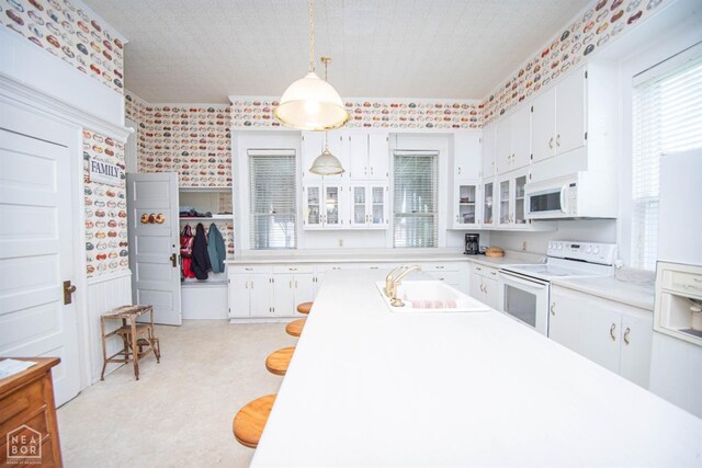 kitchen featuring a sink, white cabinetry, white appliances, and brick wall