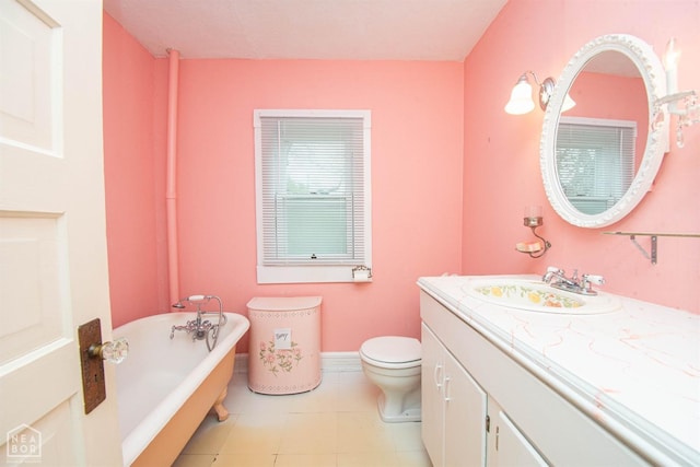 full bath with vanity, toilet, a freestanding bath, baseboards, and tile patterned floors