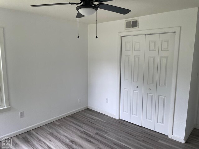 unfurnished bedroom featuring baseboards, a closet, wood finished floors, and visible vents
