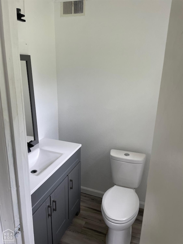 bathroom featuring visible vents, vanity, wood finished floors, toilet, and baseboards
