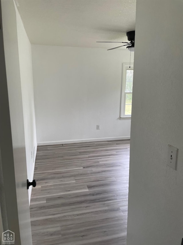 empty room featuring baseboards, ceiling fan, and wood finished floors