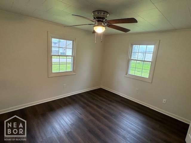 330 E Oak St E, Bono, AR 72416 - empty room with healthy amount of natural light, dark wood-type flooring, and a ceiling fan