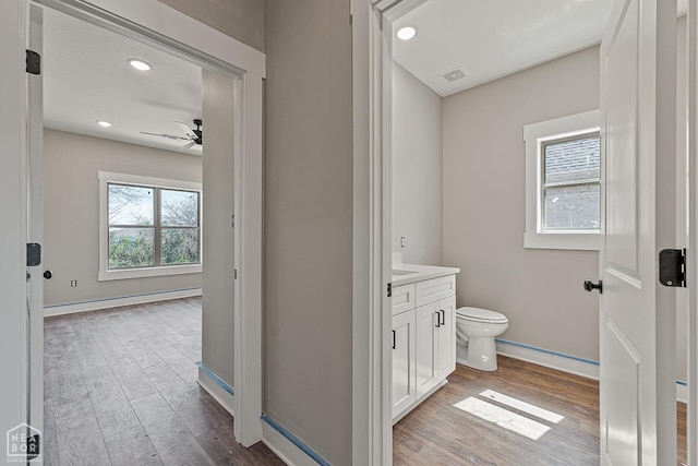 bathroom featuring toilet, baseboards, ceiling fan, vanity, and wood finished floors