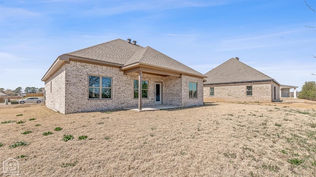 back of house with a patio, a shingled roof, and brick siding