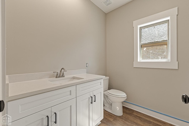 bathroom featuring toilet, baseboards, visible vents, vanity, and wood finished floors