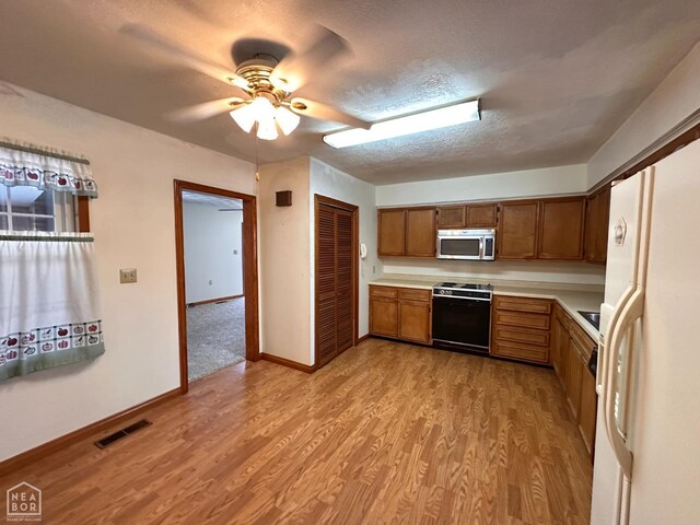 245 S 18th St, Piggott, AR 72454 - kitchen with stainless steel microwave, range, light wood-style flooring, light countertops, and visible vents
