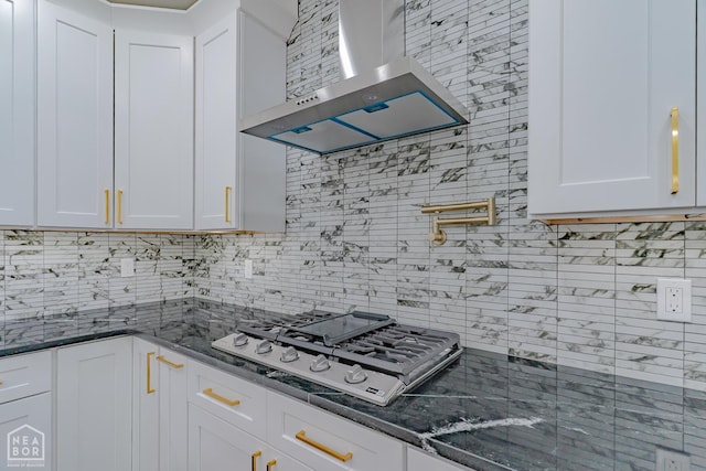 400 Gia St, Bono, AR 72416 - kitchen with wall chimney exhaust hood, stainless steel gas cooktop, decorative backsplash, white cabinetry, and dark stone counters