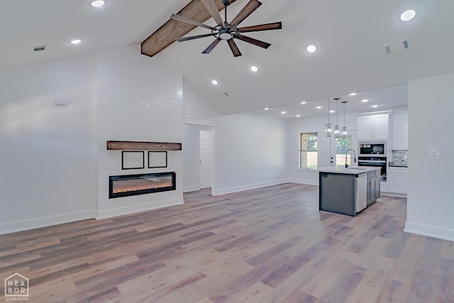 400 Gia St, Bono, AR 72416 - unfurnished living room featuring a ceiling fan, a large fireplace, beam ceiling, high vaulted ceiling, and light wood-style floors