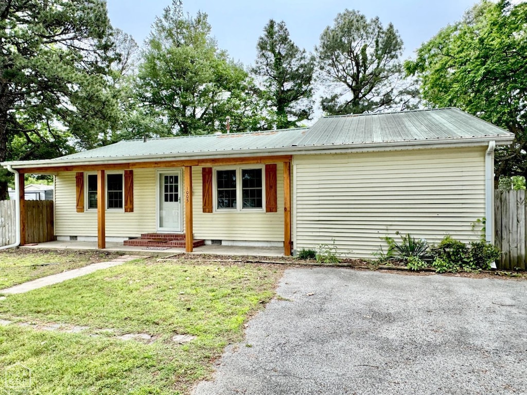 ranch-style house with covered porch, crawl space, fence, metal roof, and a front lawn