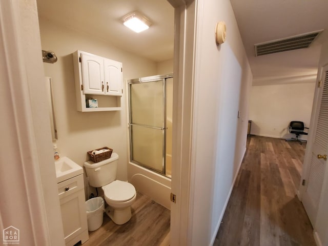 full bathroom featuring combined bath / shower with glass door, vanity, toilet, visible vents, and wood finished floors