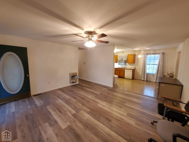 unfurnished living room featuring light wood-style flooring, ceiling fan, baseboards, and heating unit