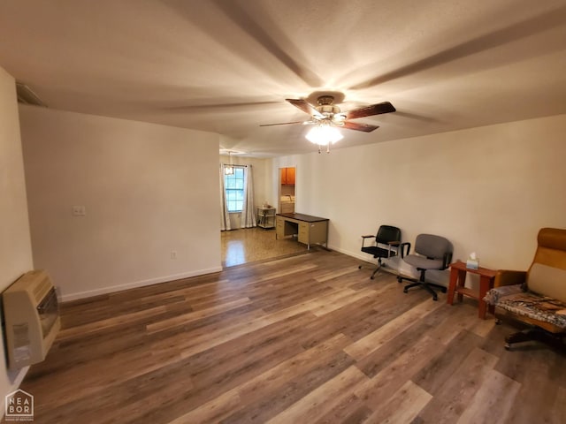 unfurnished room featuring baseboards, a ceiling fan, heating unit, and wood finished floors