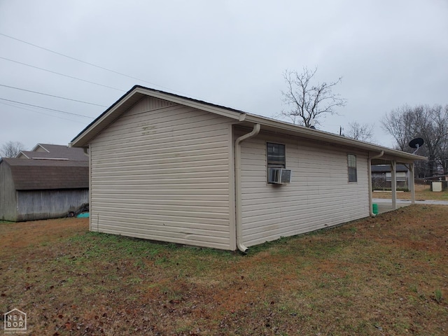 view of side of home featuring a yard, a storage shed, cooling unit, and an outbuilding