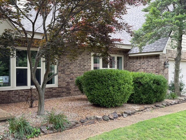 318 Davis St, Manila, AR 72442 - view of side of home featuring brick siding, a shingled roof, and a garage