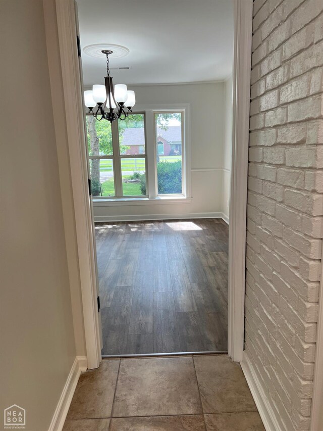 318 Davis St, Manila, AR 72442 - unfurnished dining area with a chandelier, brick wall, and wood finished floors