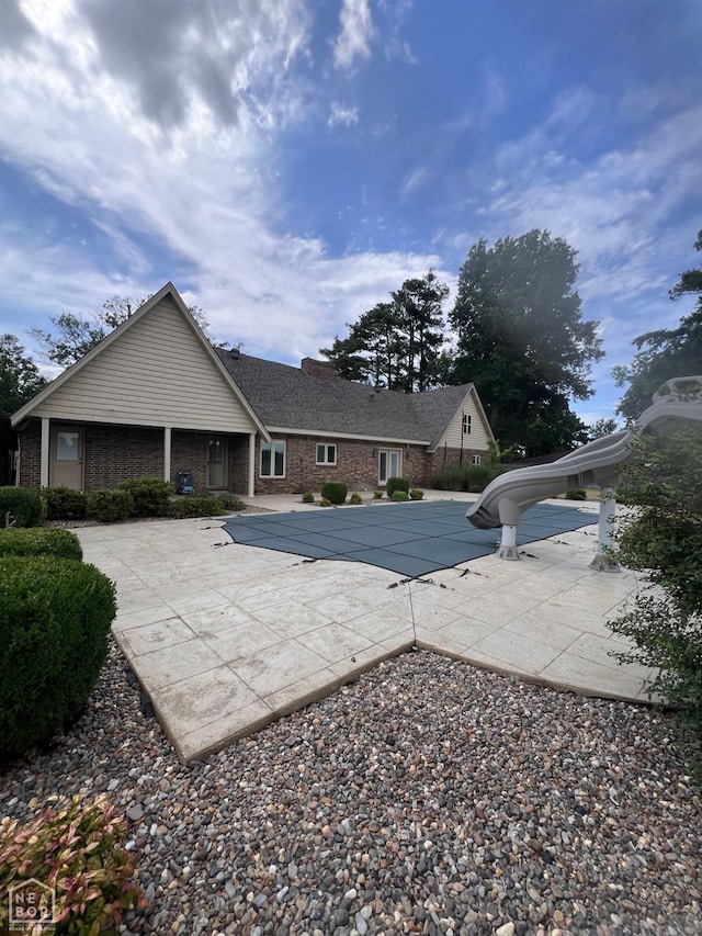 318 Davis St, Manila, AR 72442 - rear view of house featuring a patio area, a covered pool, brick siding, and a chimney