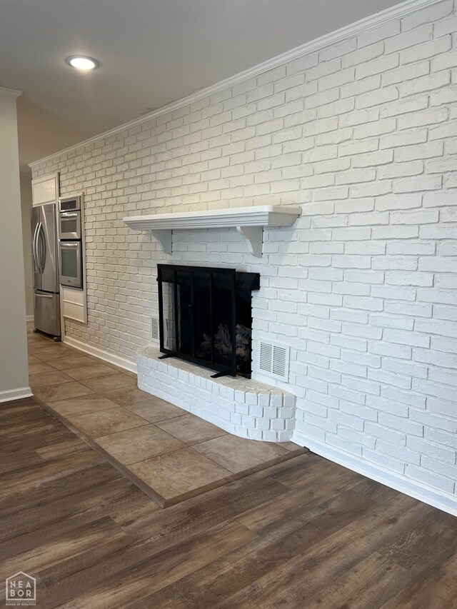 318 Davis St, Manila, AR 72442 - detailed view of crown molding, freestanding refrigerator, a fireplace, brick wall, and wood finished floors