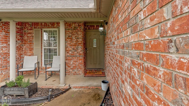 328 Natchez Dr, Jonesboro, AR 72404 - property entrance featuring brick siding, roof with shingles, and a porch