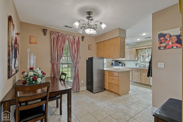 328 Natchez Dr, Jonesboro, AR 72404 - kitchen with freestanding refrigerator, light brown cabinets, light countertops, light tile patterned floors, and a chandelier