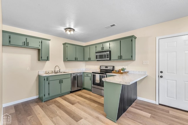 202 S 14th Ave, Paragould, AR 72450 - kitchen featuring appliances with stainless steel finishes, a sink, a peninsula, light countertops, and light wood-style flooring