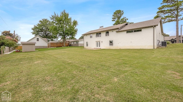 rear view of property featuring cooling unit, fence, and a lawn